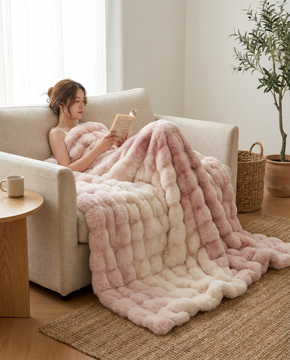 Woman reading on a sofa under the Blush Haze Snuglux blanket