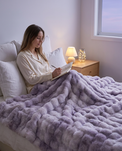 Snuglux blanket in Twilight across a bed at dusk